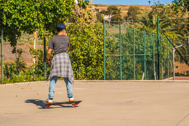 Junge auf dem Rücken Schlittschuh laufen mit seinem Skateboard in einem Skatepark - Foto, Bild