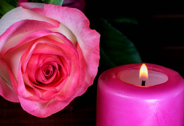 Ένα κερί καίει δίπλα σε λευκά-κόκκινα τριαντάφυλλα αναμνηστική σύνθεση close-up - Φωτογραφία, εικόνα