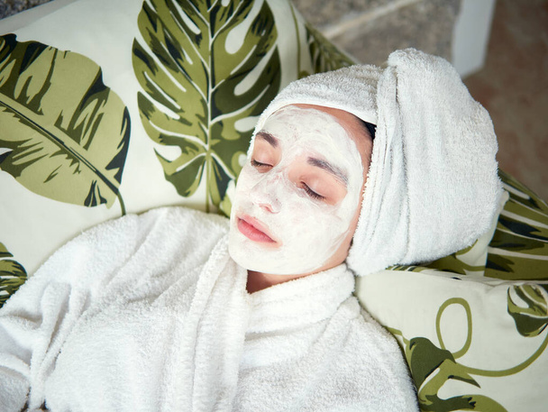 adolescente que se relaja con una máscara facial hidratante en la cara - Foto, Imagen
