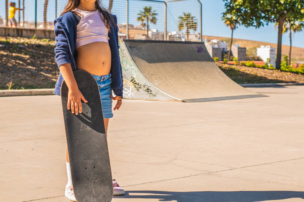 Retrato de uma menina patinadora caucasiana irreconhecível com seu skate em um parque de skate - Foto, Imagem