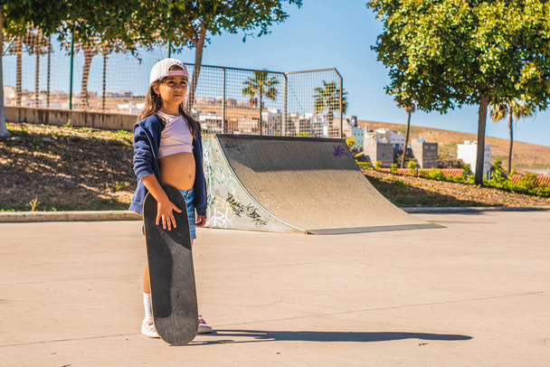 Portrait of a Caucasian skater girl with her skateboard in a skate park - Photo, Image