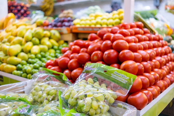 Farbenfroher Gemüse- und Obststand mit Tomaten, Trauben, Mangos und mehr - Foto, Bild