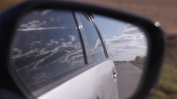 close-up van bewegend zicht in auto achteruitkijkspiegel van wolken en veld. Reizen met de auto concept. - Video