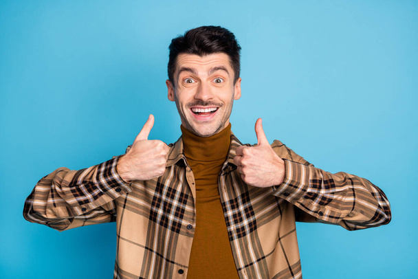 Photo of young happy excited smiling cheerful good mood man showing thumb-up isolated on blue color background - Foto, immagini