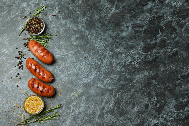 Grillezett kolbász, mustár és fűszerek fekete füstös háttérrel - Fotó, kép