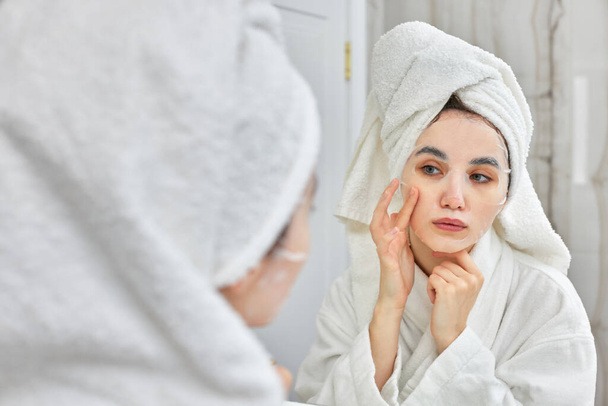 woman in white bathrobe in front of mirror in bathroom - Фото, зображення