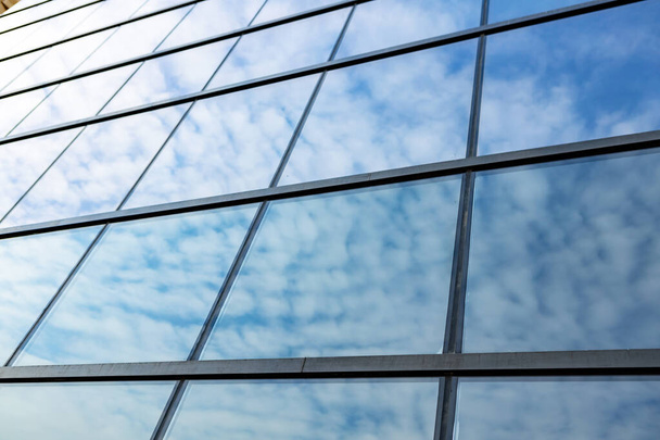 Glass skyscraper against blue sky, view from bottom - 写真・画像