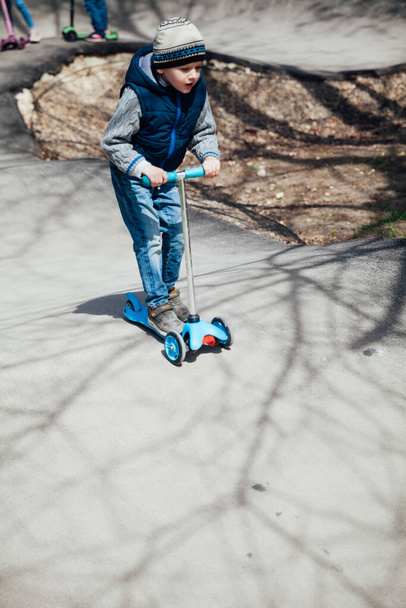 Petit garçon monte un scooter sur les routes dans l'aire de jeux - Photo, image