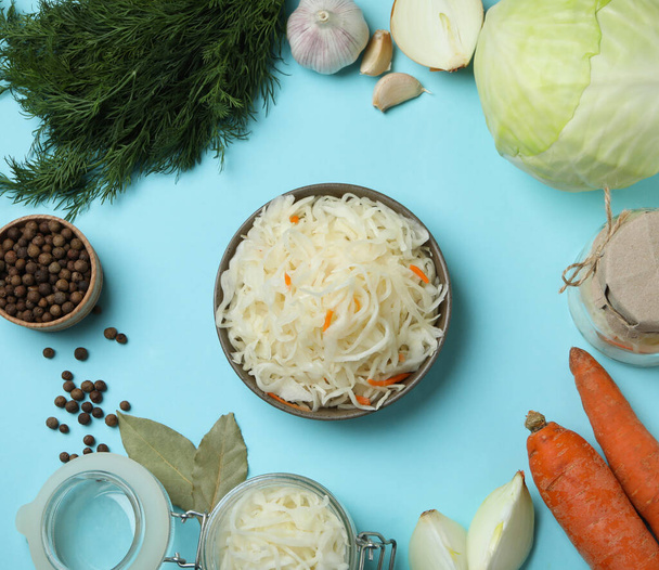 Fresh sauerkraut and ingredients on blue background - Zdjęcie, obraz