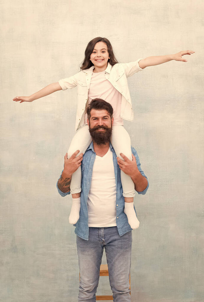 Happy father ride daughter child on shoulders pretending flying playing airplane grey background, fathers day - Фото, зображення
