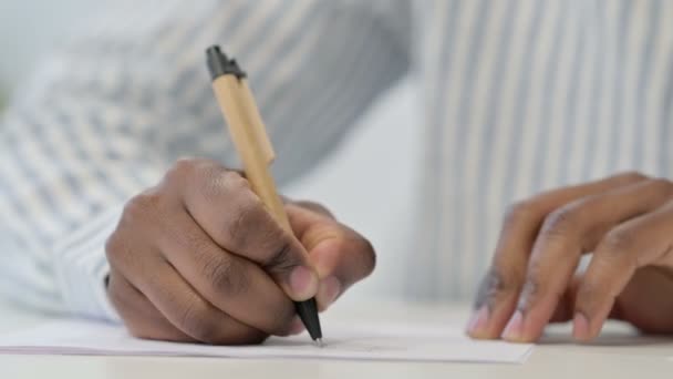 ペンで紙に書くアフリカ人の男の終わり  - 映像、動画