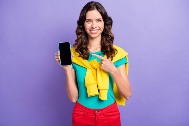 Portrait of pretty cheerful wavy-haired girl holding in hand demonstrating device recommend isolated over violet pastel color background - Foto, Bild