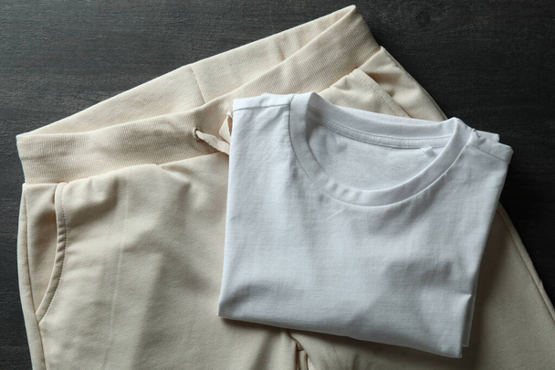 Λευκό t-shirt και φόρμες σε σκούρο ξύλινο φόντο - Φωτογραφία, εικόνα