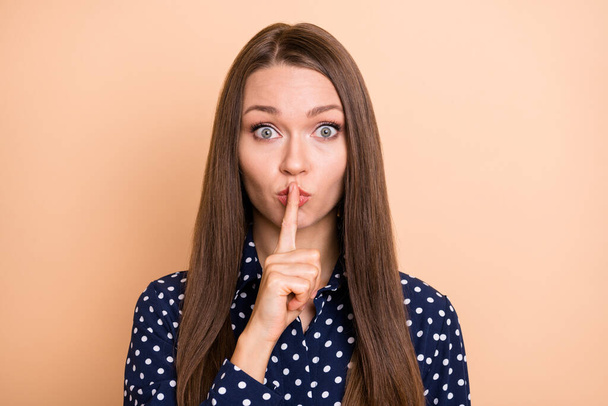 Photo of impressed cute young girl dressed dotted blouse finger lips ask not tell secrets isolated beige color background - Photo, Image