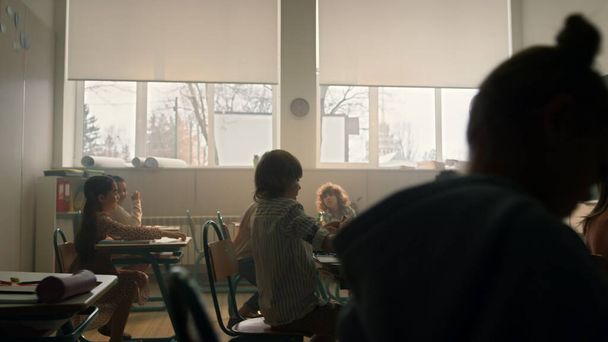 Τα παιδιά μαθαίνουν στη σχολική τάξη. Γυναίκα δασκάλα στέκεται μπροστά από την τάξη - Φωτογραφία, εικόνα
