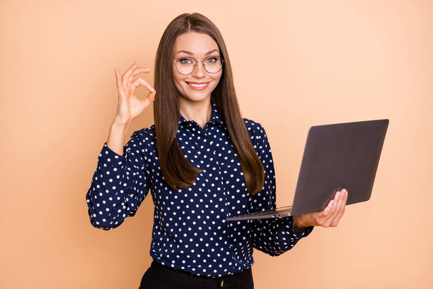 Photo of young business woman show okey deal done cool sign hold laptop project report isolated over beige color background - Φωτογραφία, εικόνα