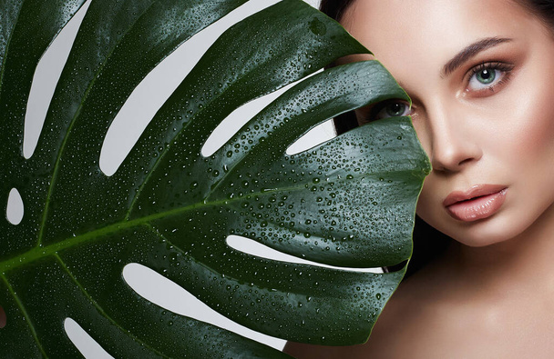 beautiful girl in palm leaves. Beautiful young woman with Make-up. Beauty Portrait. Natural cosmetics - Фото, изображение