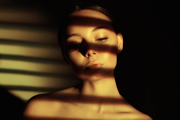 light on the face of beautiful girl. sensual young woman in shadows - Фото, изображение