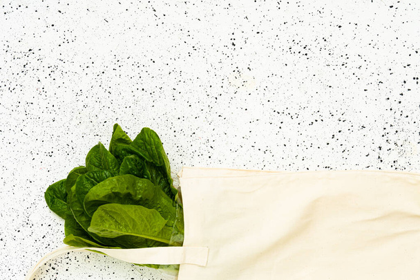 Salade de laitue en éco-sac blanc sur fond blanc concept zéro déchet. Salat juteux mûr eco bio fond frais vue de dessus - Photo, image