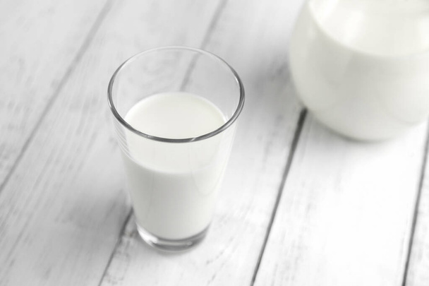 Szklanka pełna świeżego mleka roślinnego lub krowiego stoi na białym drewnianym stole. fermentowana żywność. - Zdjęcie, obraz