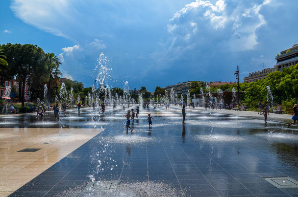 Waterspelen op de Promenade du Paillon in Nice. Waterreflecterende fontein omgeven door prachtige historische gebouwen. Nice, Frankrijk - Foto, afbeelding