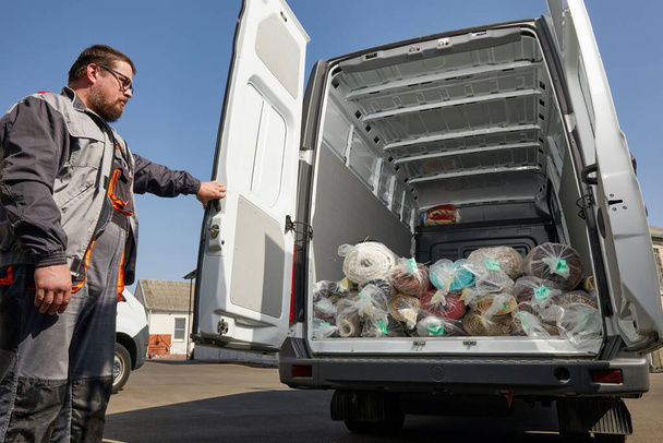 Lavoratore in piedi vicino a camion pieno di tappeti. concetto di servizio di pulizia - Foto, immagini