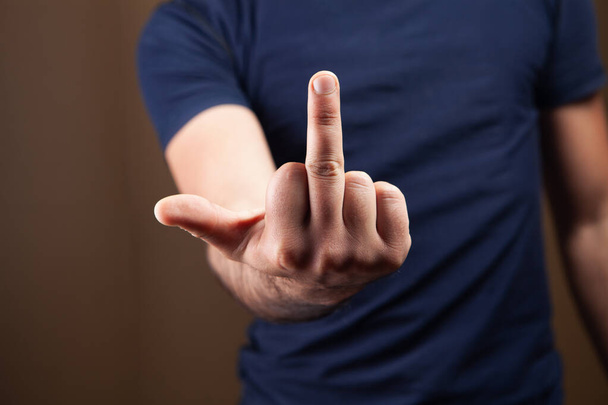 мужчина показывает средний палец на коричневом фоне - Фото, изображение