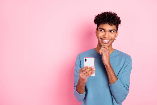 Photo of optimistic nice brunet guy look empty space write telephone wear blue sweater isolated on pastel pink color background - Fotó, kép