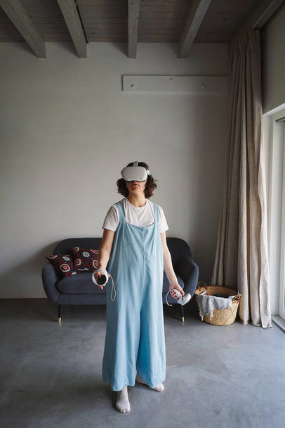 Γυναίκα με γυαλιά VR που βιώνει την εικονική πραγματικότητα στο σπίτι - Φωτογραφία, εικόνα