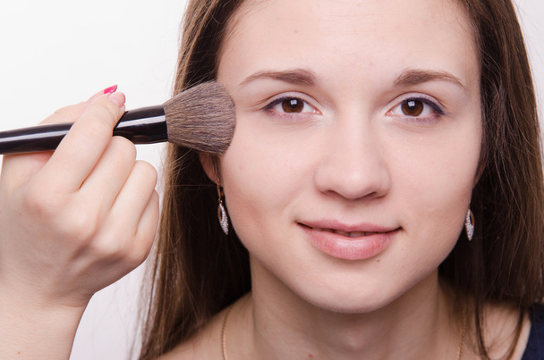 καλλιτέχνης μακιγιάζ ισχύει σκόνη στα μάγουλα της ένα όμορφο κορίτσι - Φωτογραφία, εικόνα