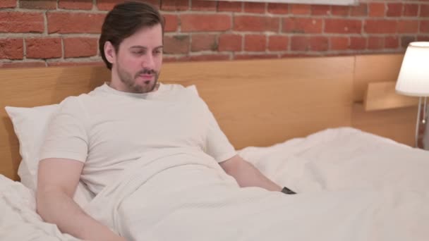 Lässiger junger Mann mit Rückenschmerzen im Bett - Filmmaterial, Video