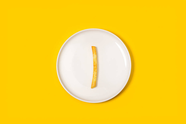 Eine Bratkartoffel auf einem weißen Teller auf gelbem Hintergrund in einer Draufsicht - Foto, Bild
