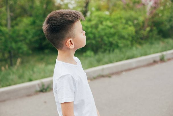 Retrato de menino bonito na moda em branco T-shirt ao ar livre no parque. Conceito de estilo e moda para crianças. Conceito Mockup - Foto, Imagem