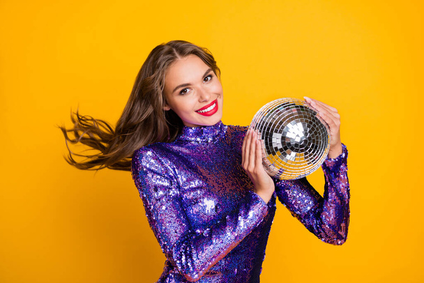 Photo of young attractive fancy girl happy positive smile hold disco ball isolated over yellow color background - Fotó, kép