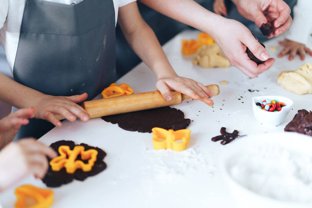 Boy rolls out the dough, the children prepare cookies. Family business concept. - 写真・画像