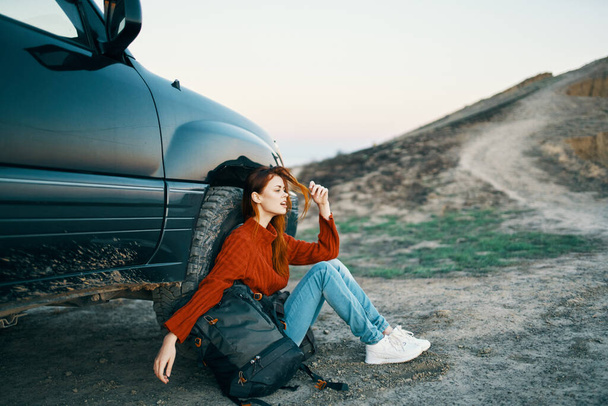 žena cestuje na přírodě v horách v blízkosti auta s batohem na boku - Fotografie, Obrázek