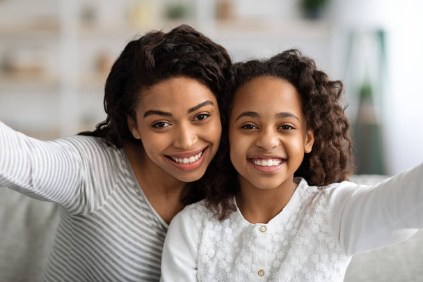 Atractiva madre negra e hija tomando selfie en casa - Foto, Imagen