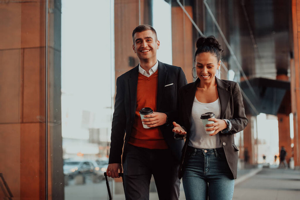 Businessman and businesswoman talking and holding luggage traveling on a business trip, carrying fresh coffee in their hands. Business concept. High-quality photo - Foto, Imagem
