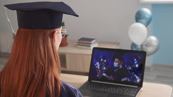 молодая очаровательная студентка в академической одежде, посещающая онлайн-выпускной с учителем-мужчиной в медицинской маске, ректор университета использует современные технологии видеокоммуникаций, чтобы выпуститься во время - Кадры, видео