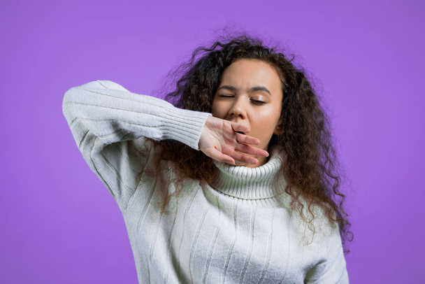 Tired sleepy woman yawns, covers her mouth with hand. Very boring, uninteresting. Violet studio background. - Foto, Imagen