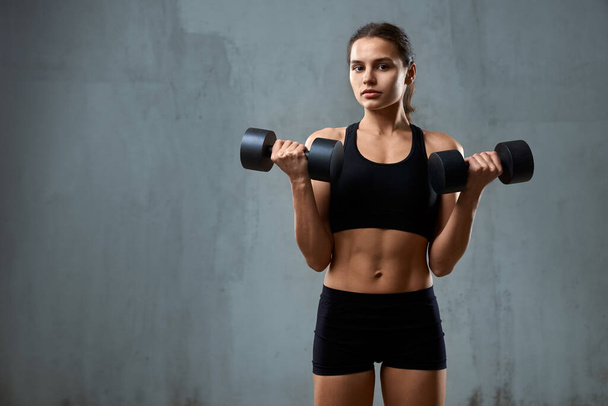 Young fitnesswoman training arms with dumbbells. - Foto, Imagem
