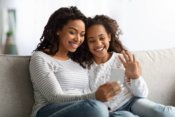 Uśmiechnięty czarny matka i córka mając wideo rozmowy na smartfonie - Zdjęcie, obraz