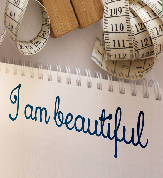 I am beautiful words written on copybook page with measure tape. Affirmation and fitness healthcare concept. - Photo, Image