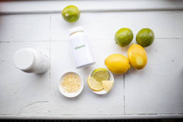 Limões, limas e garrafas de vitaminas em um balcão de cozinha branca - Foto, Imagem