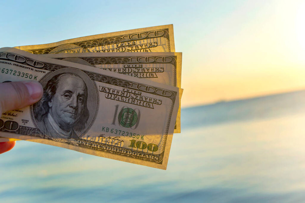 Tři sta dolarů bankovky na pozadí mořského povrchu. 100 dolarů v hotovosti - Fotografie, Obrázek