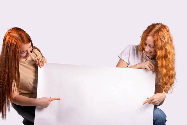 Pinup women showing forefinger hands on the blank banner photo for ad set of young caucasian pin-up red-haired models on grey background with space for text. - Fotografie, Obrázek