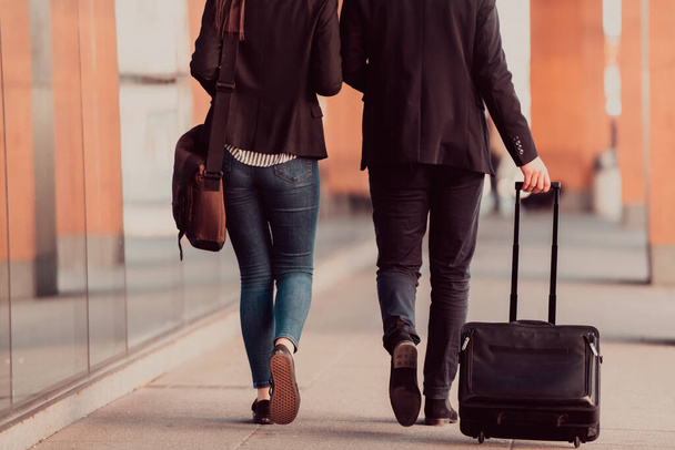 Businessman and businesswoman talking and holding luggage traveling on a business trip, carrying fresh coffee in their hands. Business concept. High-quality photo - Foto, imagen
