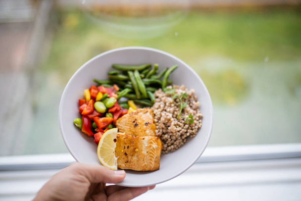 Hand holding salmon and buckwheat dish with green beans - Photo, Image