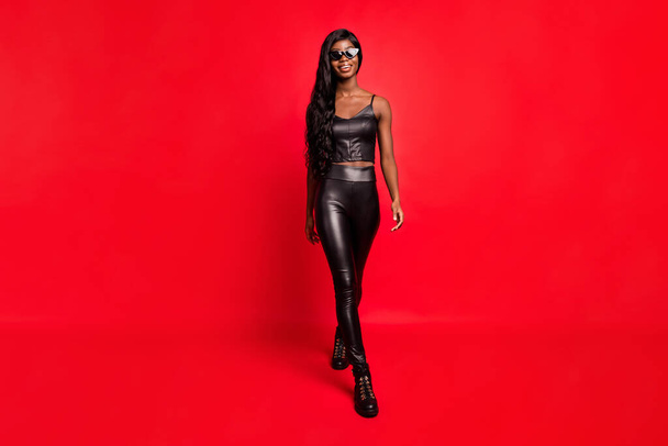 Full length body size view of charming cheery girl wearing trendy leather costume going isolated over bright red color background - Fotoğraf, Görsel
