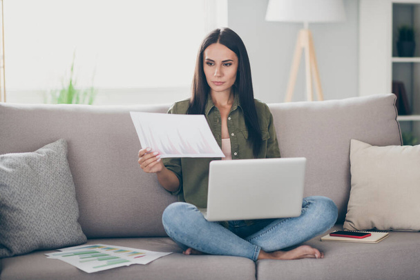 Portrait of charming skilled focused girl sitting on divan using laptop reading documents working remotely at home house flat indoor - Фото, изображение